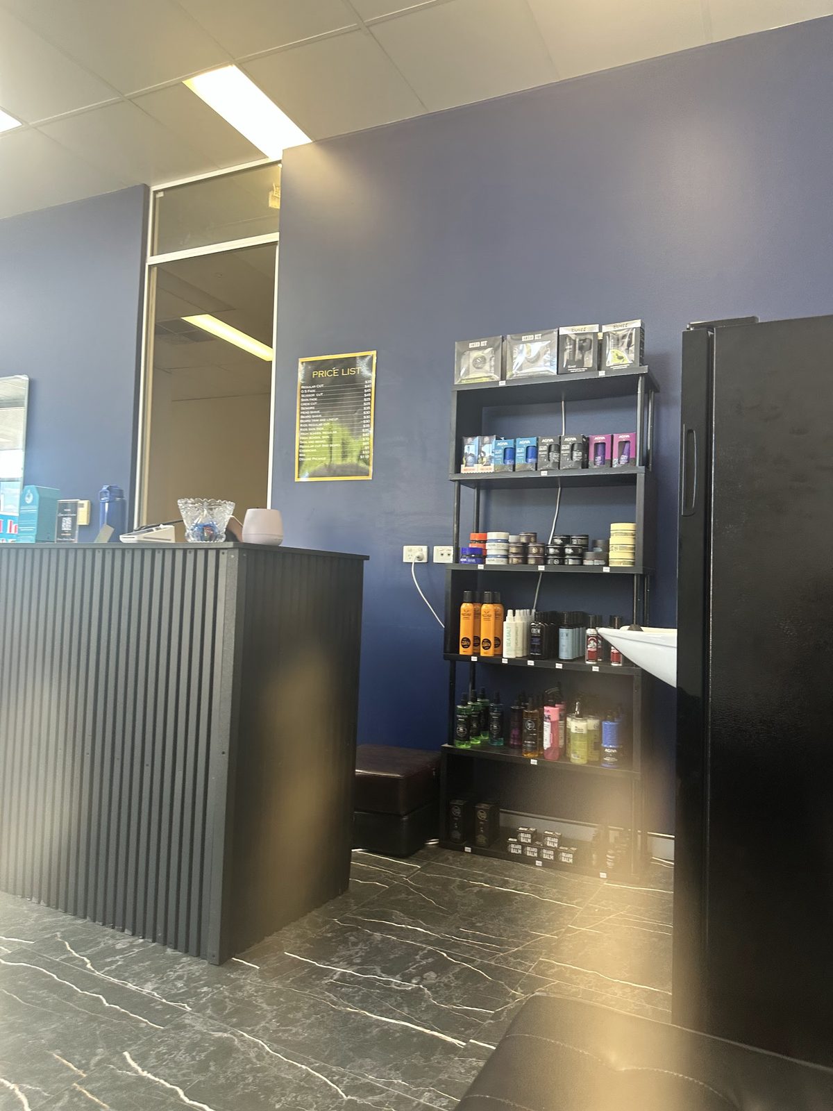 Reception counter and a wall shelf of styling products, pomades and beard care