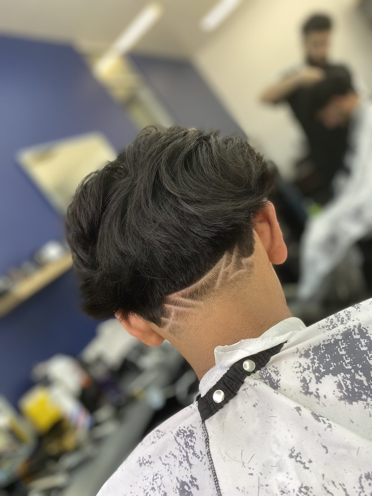 Back view of a taper with a hand-cut line design at the nape